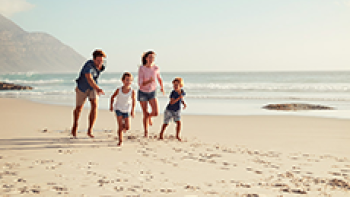 Eine Familie tobt am Sandstand im Urlaub