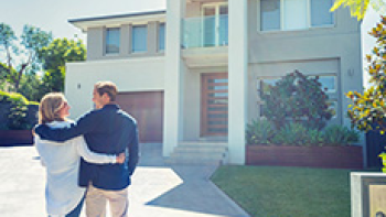 Pärchen steht glücklich vor seinem Haus