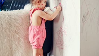 Ein Mädchen bemalt mit einem Stift die Wände eines Wohnzimmers