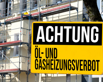 Achtungsschild vor einem eingerüsteten Haus 