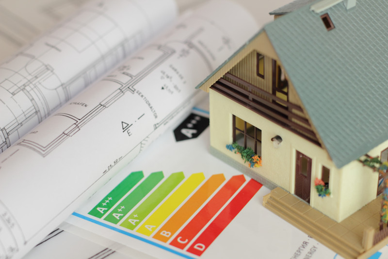 AdobeStock_57487924 Bauplan und Energieeffizienzskala auf dem ein Modellhaus steht