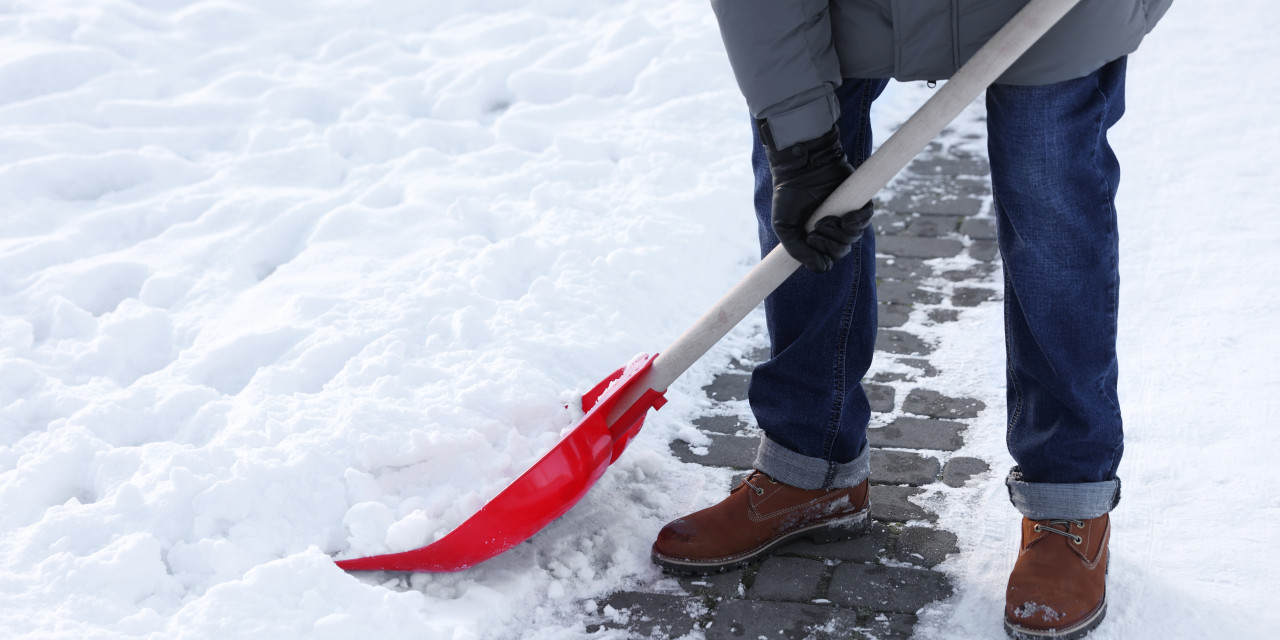 Mann, der Schnee von einem Gehweg räumt