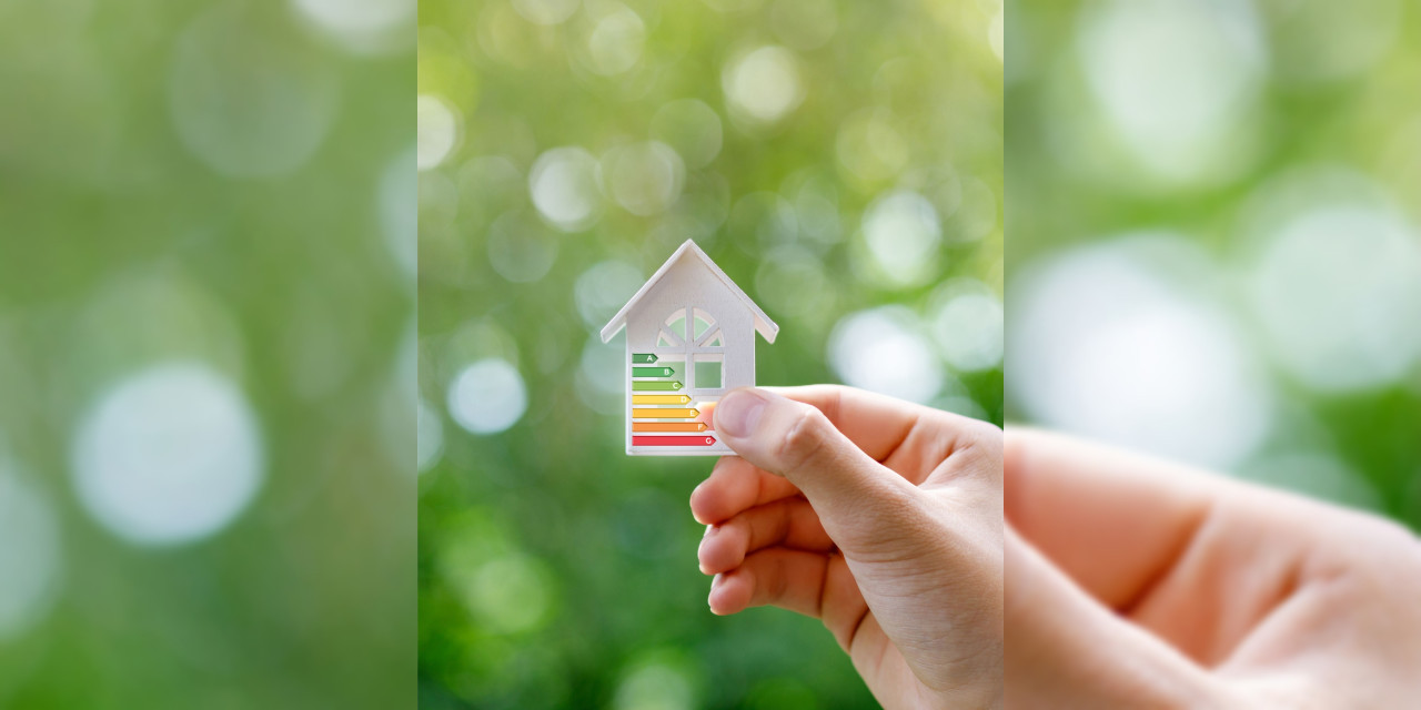 Energieberatung Kleines Haus mit Energieeffizienz-Angabe im Grünen, von Hand gehalten