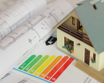 Bauplan und Energieeffizienzskala auf dem ein Modellhaus steht