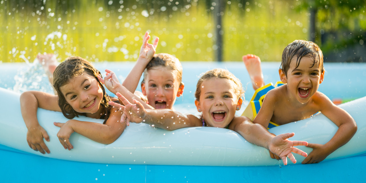 Kinder plantschen freudig im Plastik-Swimmingpool