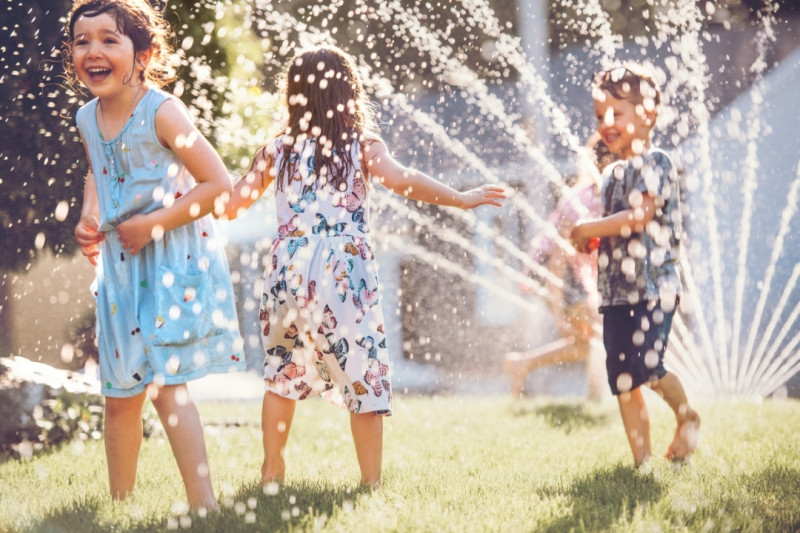Kinder die Im Garten mit Wasser spielen