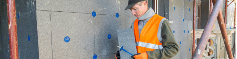 Handwerker befestigt Außendämmung an Fassade