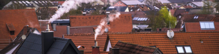 Rauchende Schornsteine über Wohngebiet