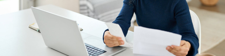 Frau arbeitet an Laptop und prüft Abrechnungen