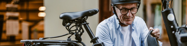 Älterer Mann wechselt E-Bike-Akku