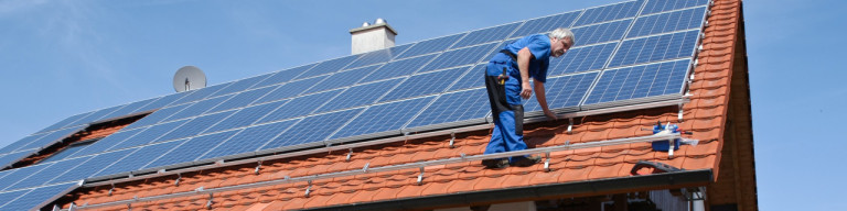 Handwerker installiert Photovoltaik auf Hausdach