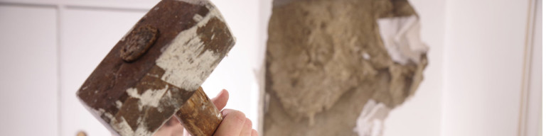 Mann reißt Wand mit Vorschlaghammer ein