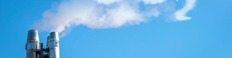 Rauch aus Schornstein bildet die Buchstaben CO² vor blauem Himmel