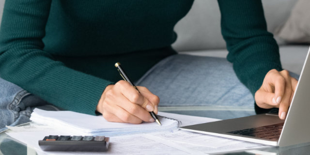 Frau mit Papieren und Laptop auf dem Sofa