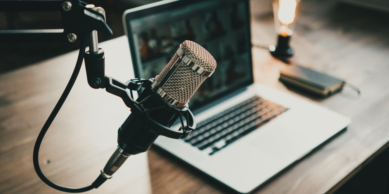 Podcast-Mikrofon vor Laptop und Lampe