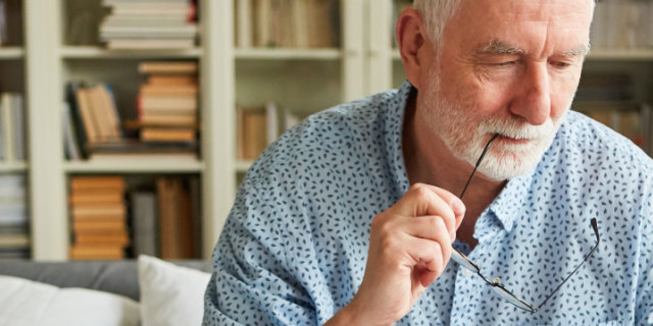 Älterer Herr denkt über Unterlagen nach