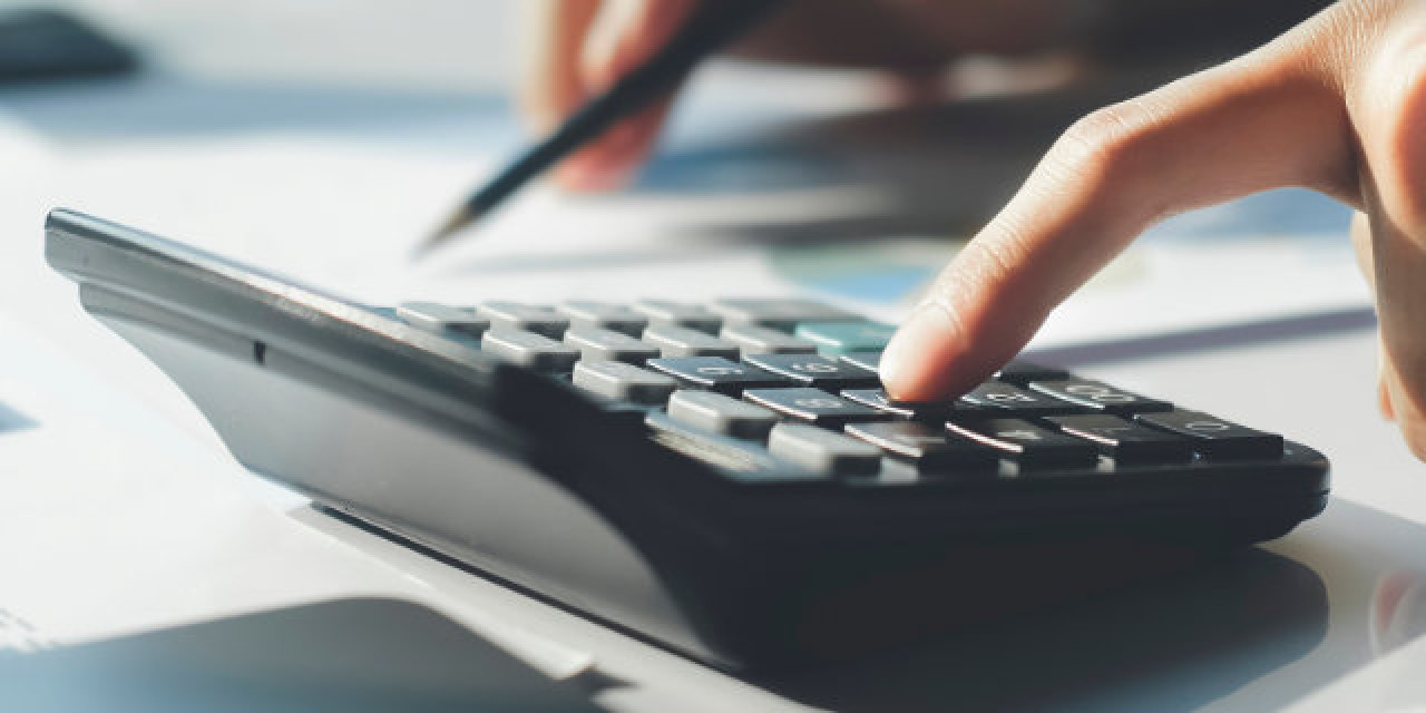 Hand mit Unterlagen und Taschenrechner