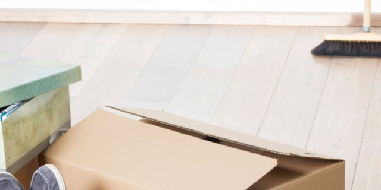 Gepackte Kartons und Schaufel und Besen in leerer Wohnung