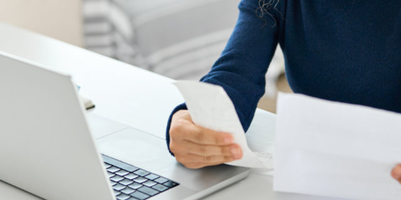 Frau arbeitet an Laptop und prüft Abrechnungen