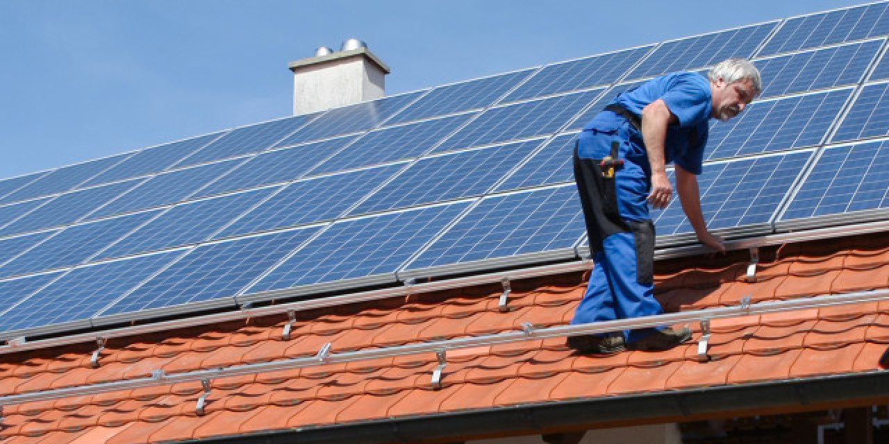 Handwerker installiert Photovoltaik auf Hausdach Handwerker installiert Photovoltaik auf Hausdach