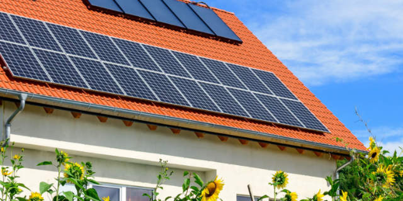 Einfamilienhaus mit Solarzellen hinter Sonnenblumen