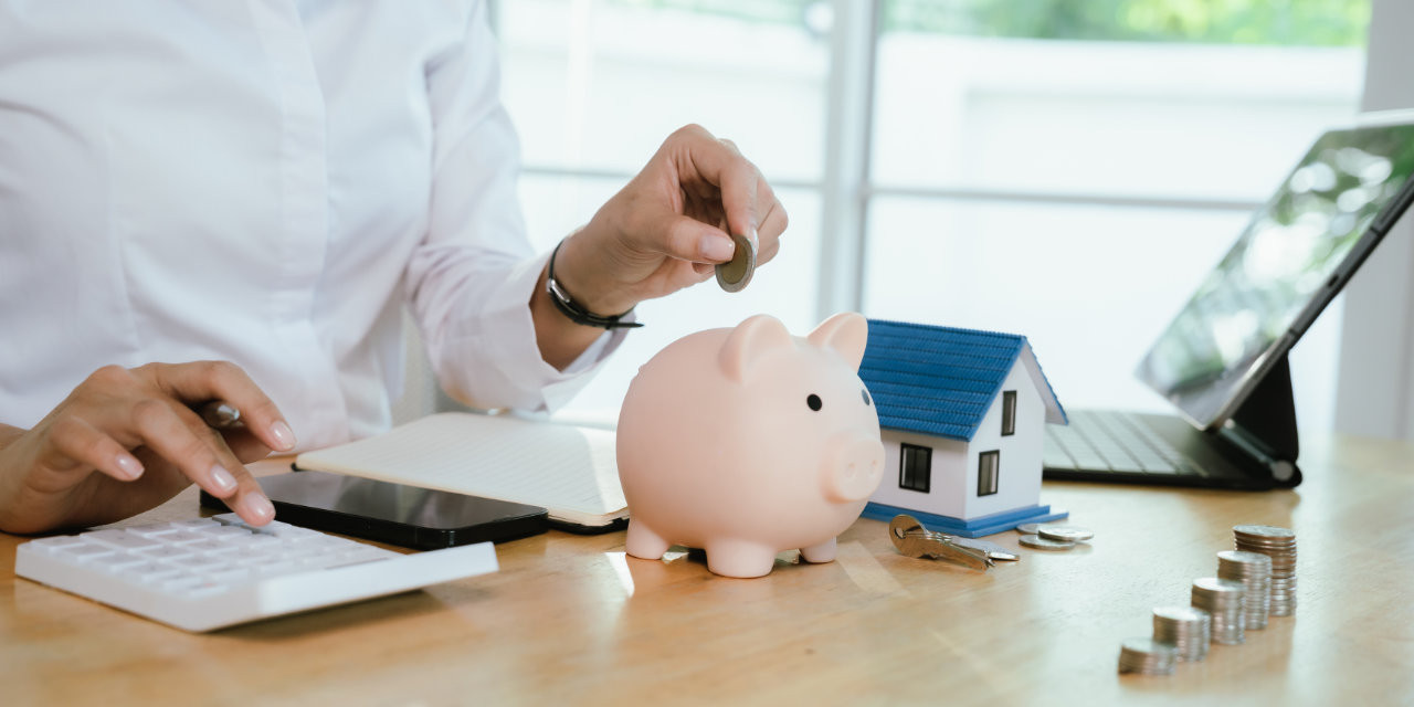 Frau macht Abrechnung und zahlt Geld in Sparschwein ein