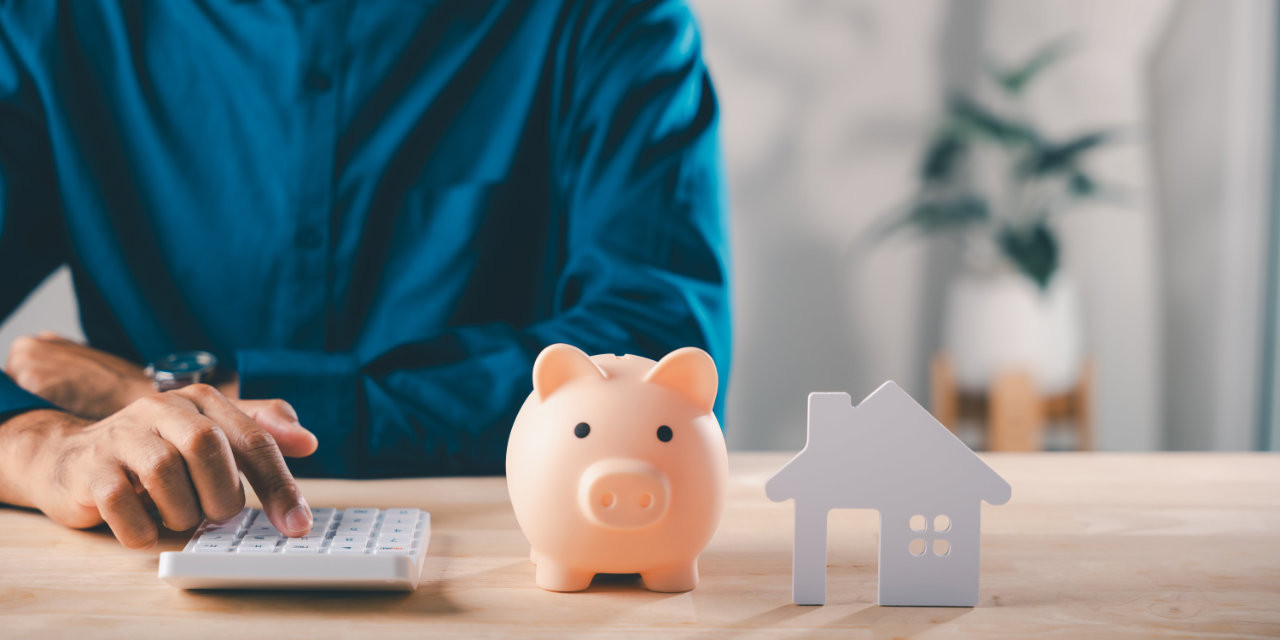 Mann mit Taschenrechner und Sparschwein