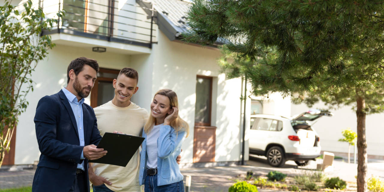 Immobilienmakler  und junges Paar vor Einfamilienhaus, Hauskauf