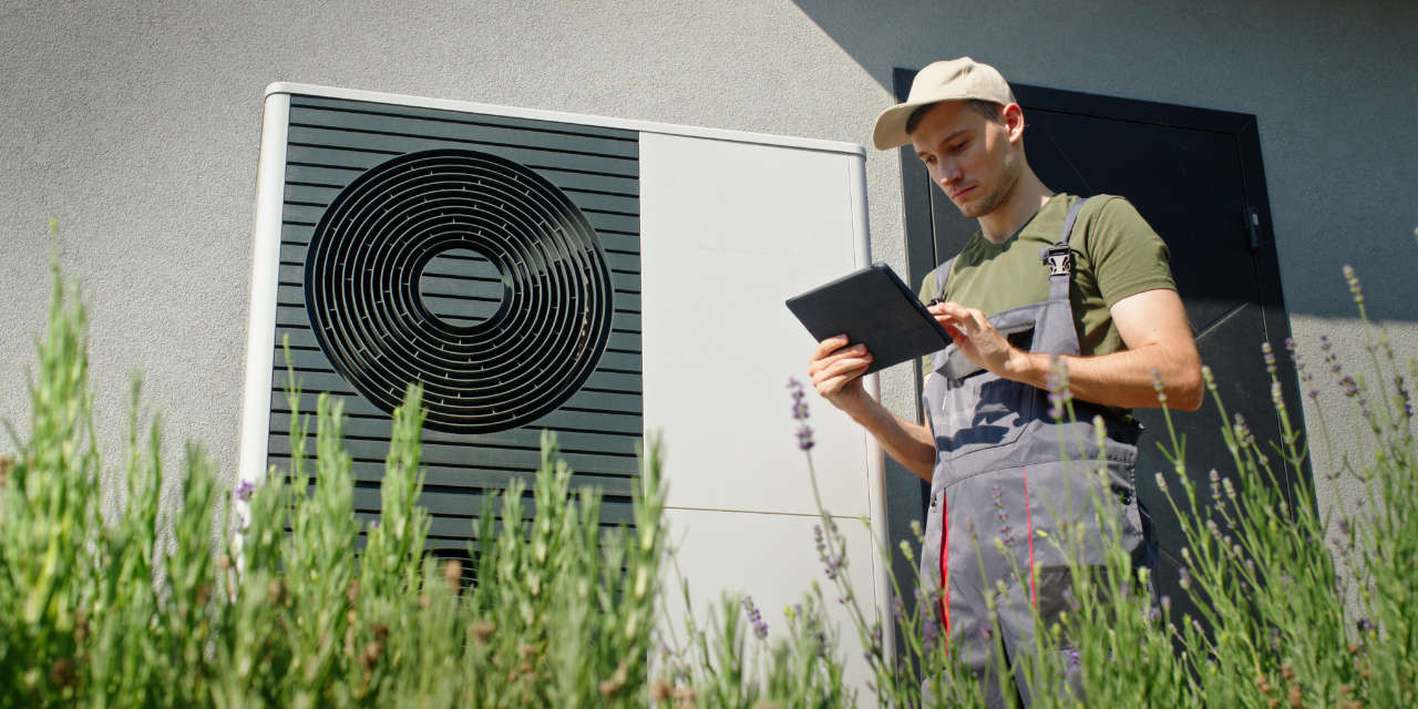 Techniker prüft Wärmepumpe an einem sonnigen Tag