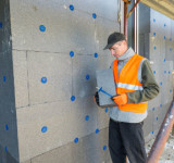 Handwerker befestigt Außendämmung an Fassade