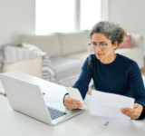 Frau arbeitet an Laptop und prüft Abrechnungen