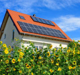 Einfamilienhaus mit Solarzellen hinter Sonnenblumen