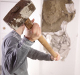 Mann reißt Wand mit Vorschlaghammer ein