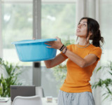 Frau fängt von der Decke tropfendes Wasser auf