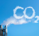 Rauch aus Schornstein bildet die Buchstaben CO² vor blauem Himmel