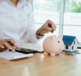 Frau macht Abrechnung und zahlt Geld in Sparschwein ein