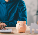 Mann mit Taschenrechner und Sparschwein