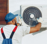 Installateur montiert Außeneinheit einer Split-Klimaanlage