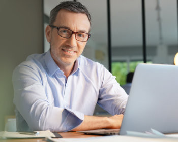 Mann mit Laptop nimmt an digitalem Seminar teil.
