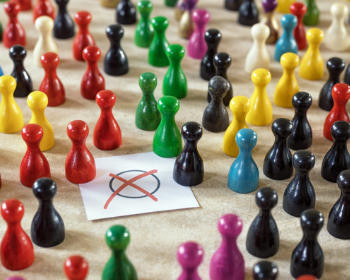 Kleine farbige Spielfiguren stehen um ein Wahlzettel-Kreuz