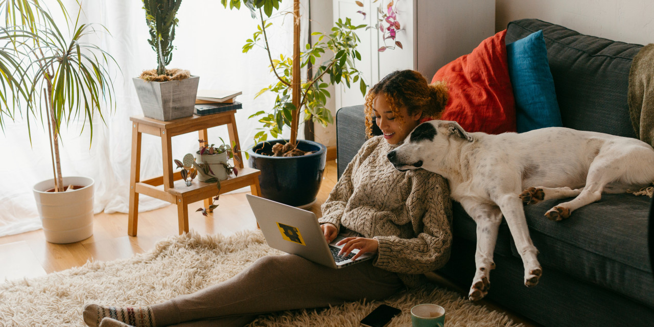Eine Frau kuschelt mit Ihrem Hund im Wohnzimmer