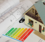 Bauplan und Energieeffizienzskala auf dem ein Modellhaus steht