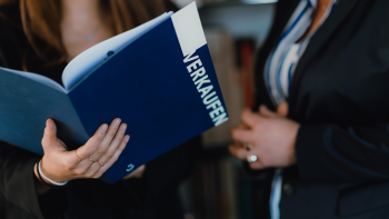 Nahaufnahme zweier Personen mit einer Mappe auf der Verkaufen steht