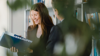 Eine Frau mit einer Verkaufsmappe und eine Frau von Hinten