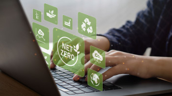 Hände tippen auf Laptop-Tastatur, darüber schwebende grüne Symbole zu Nachhaltigkeit und CO2-Reduktion.