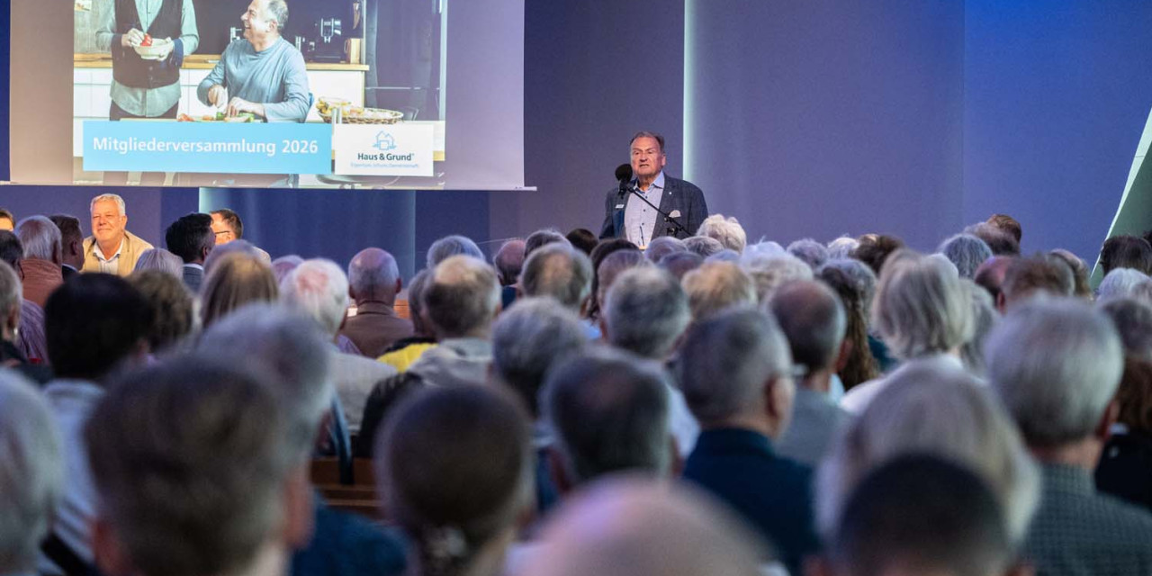 Mann spricht vor großem Publikum in einem Saal mit Präsentationsfolie im Hintergrund