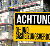 Achtungsschild vor einem eingerüsteten Haus 