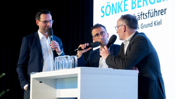 Moderator Christopher Scheffelmeier im Gespräch mit Kiels Oberbürgermeister Dr. Samet Yilmaz und Haus & Grund Kiel-Geschäftsführer Sönke Bergemann auf der Bühne.