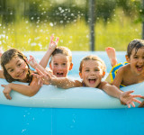 Kinder plantschen freudig im Plastik-Swimmingpool